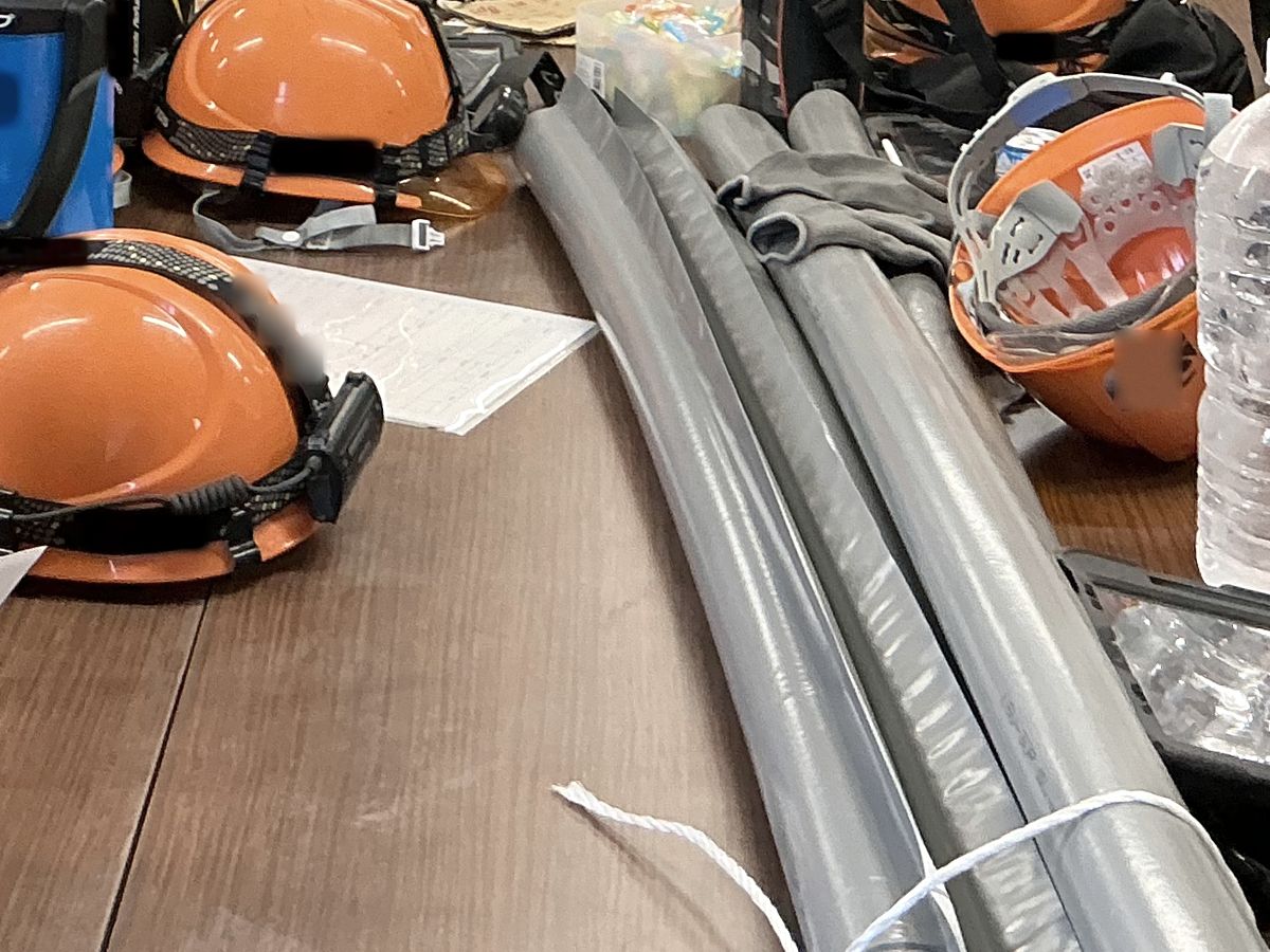 朝の打ち合わせの机に並ぶヘルメットと電線管